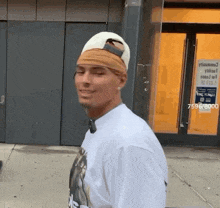 a man wearing a white hat and a bandana on his head is walking down the street .