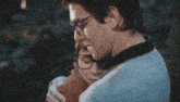 a man wearing glasses is hugging a woman