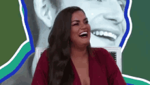 a woman in a red dress is laughing in front of a painting of a man .