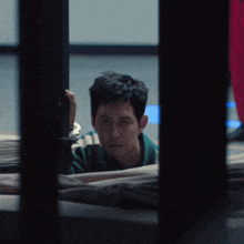 a man in a green and white striped shirt looks out of a window