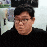a man wearing glasses and a black shirt is looking at the camera