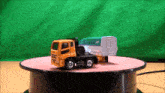a toy truck is sitting on a table with a green screen behind it
