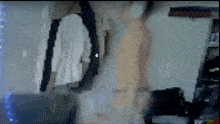 a blurry picture of a person standing in a room with clothes hanging on a wall .