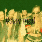 a group of people are dancing in front of a green background with the words #stay mad written on it