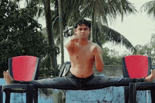a man without a shirt is doing a split on a chair