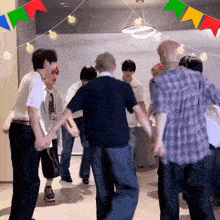 a group of people are dancing in a room with colorful flags