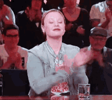a woman is clapping her hands in front of a crowd of people