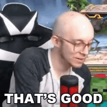 a bald man with glasses is sitting in front of a microphone .