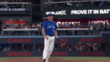 a man in a blue jays jersey stands in front of a sign that says prove it
