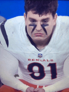 a man wearing a bengals jersey sits on the bench