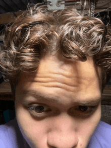 a close up of a man 's forehead with a purple shirt on