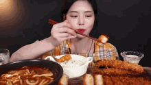 a woman is eating food with chopsticks and a spoon .
