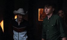a man in a cowboy hat and a man in a green shirt are standing next to each other