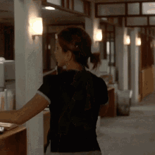 a woman wearing a black shirt is standing in a hallway