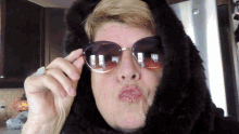 a woman wearing sunglasses and a fur coat is making a face
