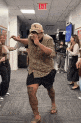 a man is dancing in a hallway with an exit sign above him