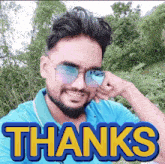 a man wearing sunglasses and a blue shirt with the words thanks on it