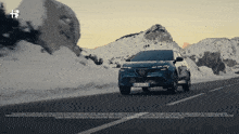 a blue car is driving down a snowy road with a license plate that says xk 88 jc