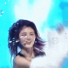 a woman with purple hair is smiling in front of a blue backdrop