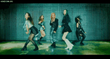 a group of young women are dancing in front of a green wall .