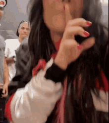 a woman is holding her finger to her lips and making a silence sign .