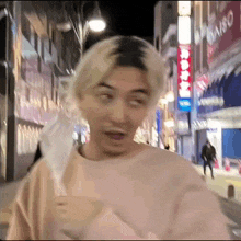 a man wearing a pink shirt is walking down a street holding a white object .