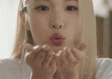 a close up of a woman blowing a kiss from her hands