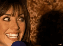 a close up of a woman 's face with a microphone in her hand .