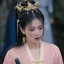a woman wearing a crown and earrings looks down at something