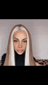 a woman with long blonde hair and white highlights is wearing a black turtleneck sweater .