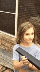 a young girl is holding a black object in her hand