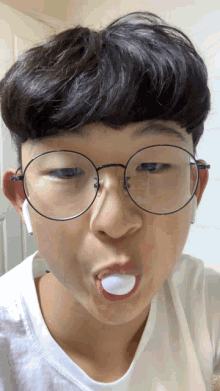 a young man wearing glasses and ear buds is making a funny face with his mouth open