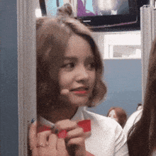 a girl in a white shirt with a red bow tie is smiling