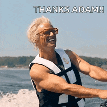 a man wearing a life jacket is riding a water ski and says thanks adam !