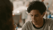 a man with curly hair is sitting at a table talking to a woman .