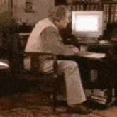 an elderly man sits in front of a computer monitor