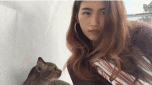 a woman is holding a cat in her arms while looking at the camera .