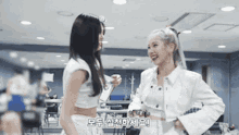 two women are standing next to each other in a room and talking to each other .