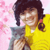 a girl in a yellow shirt is holding a kitten