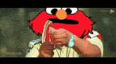 a cartoon of elmo holding a piece of meat in his hand .