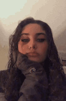 a woman wearing a champion sweatshirt has her hand on her chin