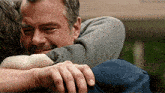 a man is hugging another man with his eyes closed