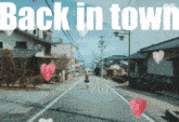 a woman walking down a street with the words back in town written above her