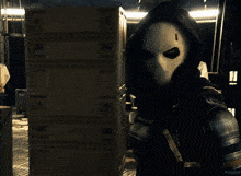 a man in a black suit is kneeling down in a dark room with boxes on the floor that say ' a ' on them