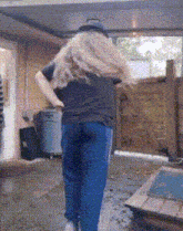 a woman in a black shirt and blue pants is standing in a garage