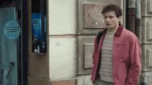 a man wearing a pink jacket stands in front of a machine that says ici