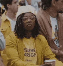 a woman wearing a yellow shirt that says believe aright