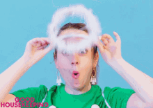 a woman wearing a green shirt and a white angel halo on her head .