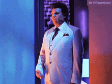a man in a suit and tie stands in front of a sign that says dr pflaumisen