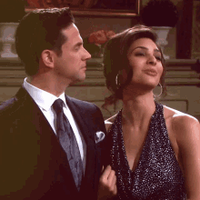 a man in a suit and tie looks at a woman in a dress